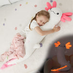 Child sleeping with a large plush toy resembling a cartoon character on a soft surface.