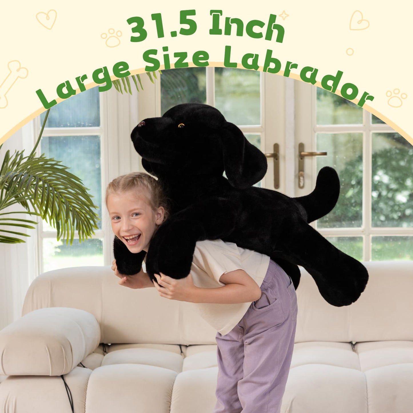 Child holding a large black stuffed Labrador toy in a living room.